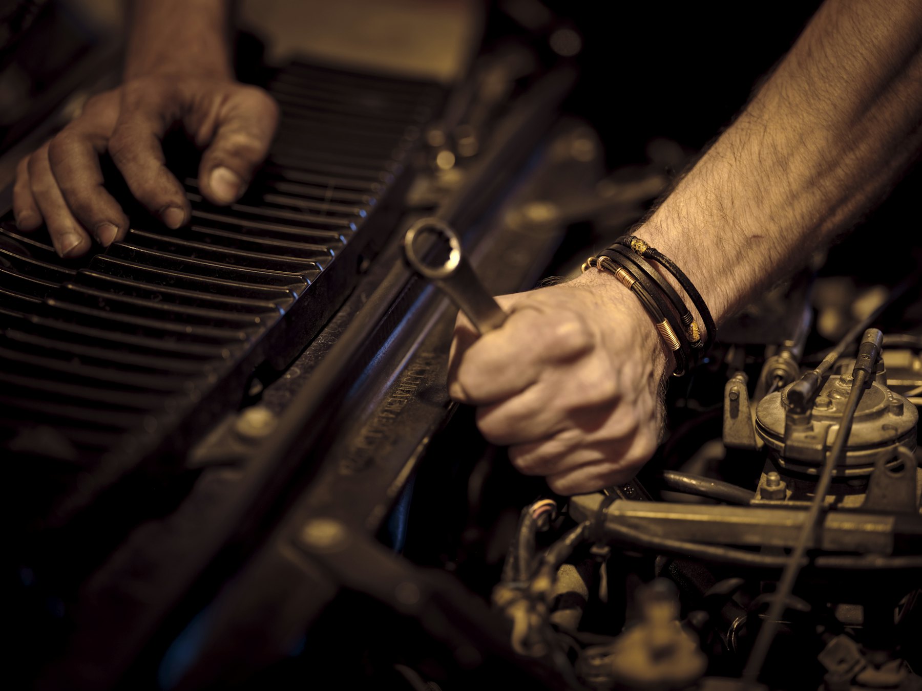 Mechanic tightening a bolt in an engine bay with a wrench