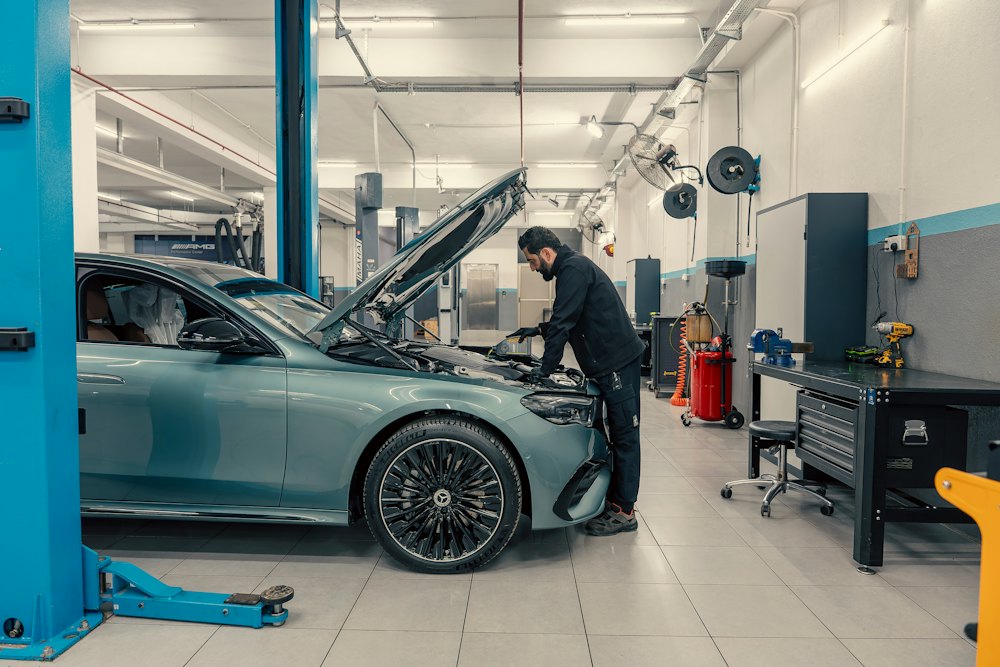 Technician inspecting a car under the hood in a clean service bay